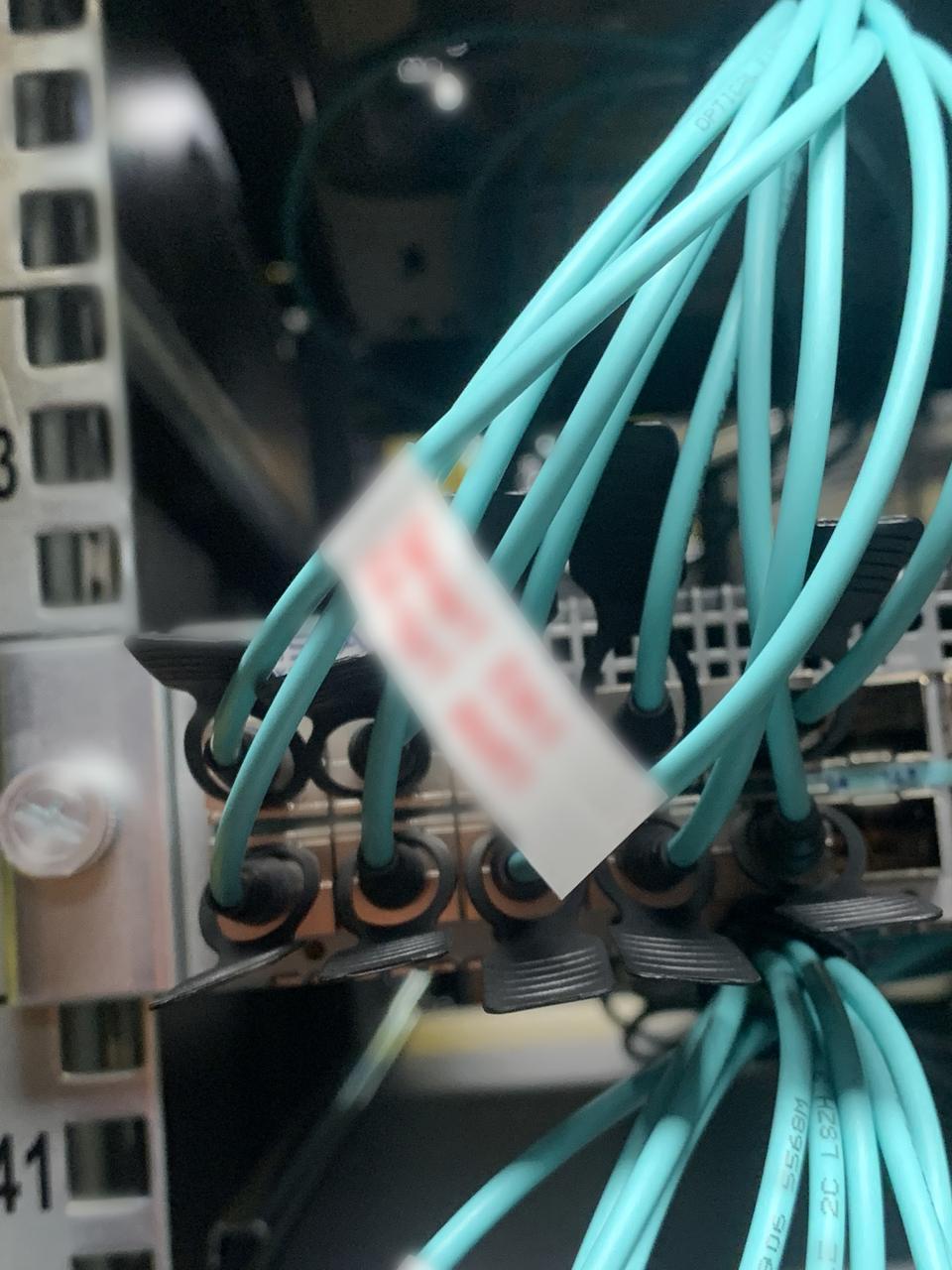 Bundle of aqua fibre leads with a label at the switch; label text blurred