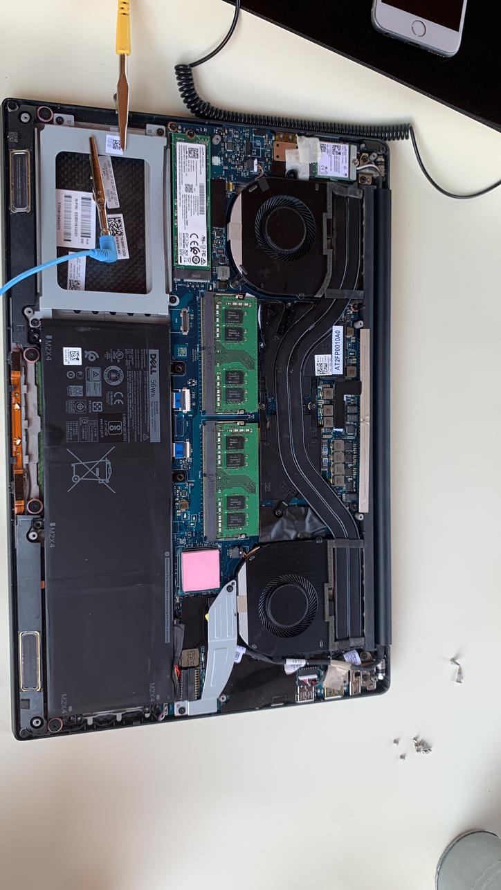 Open laptop showing memory modules, fans and battery during repair