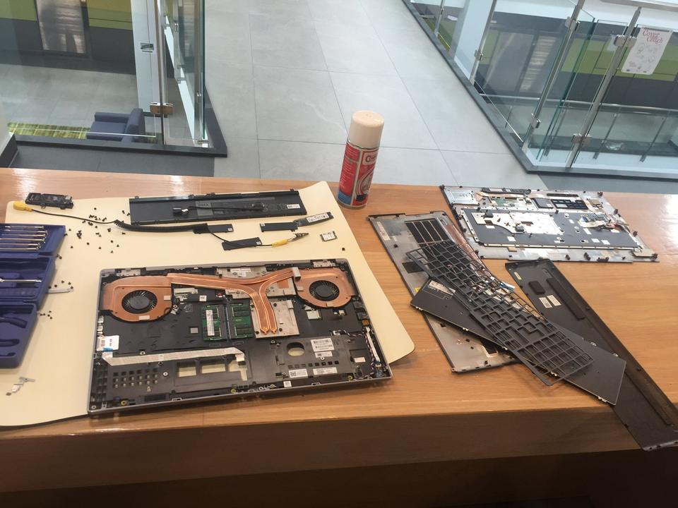 Laptop disassembled on a desk with keyboard and parts laid out