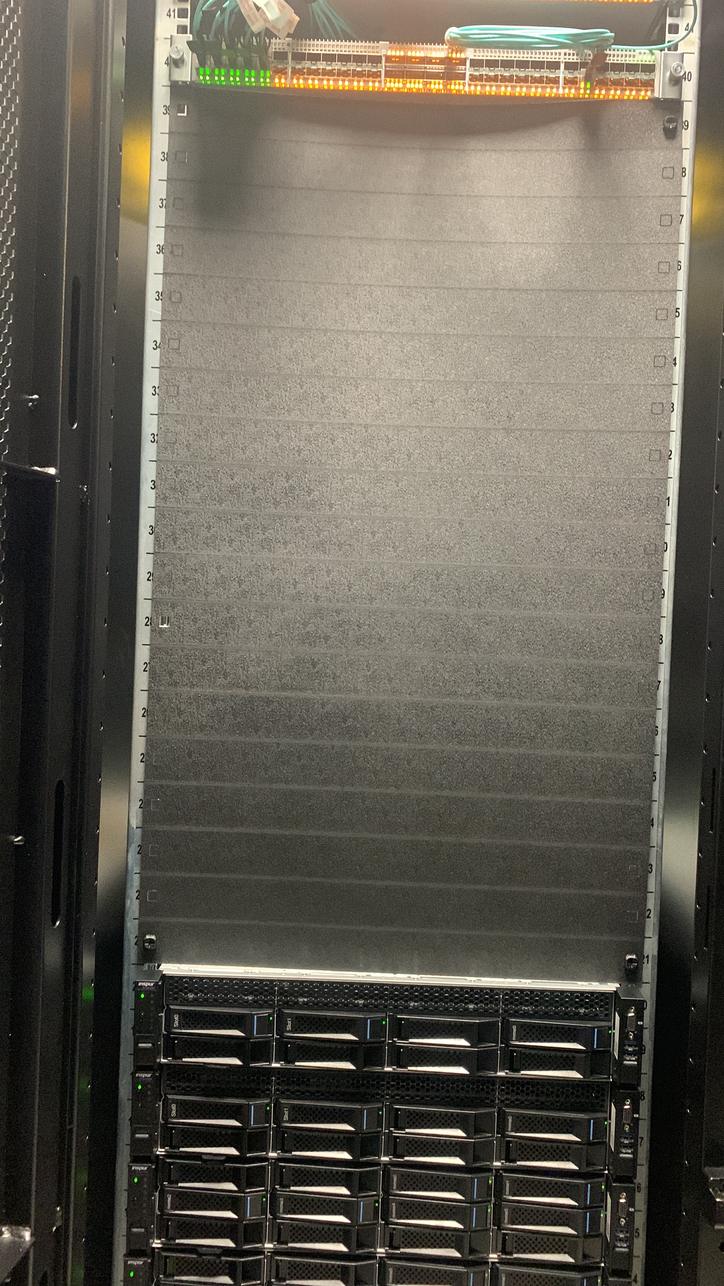 Tall rack with a chassis installed below a fibre patch panel