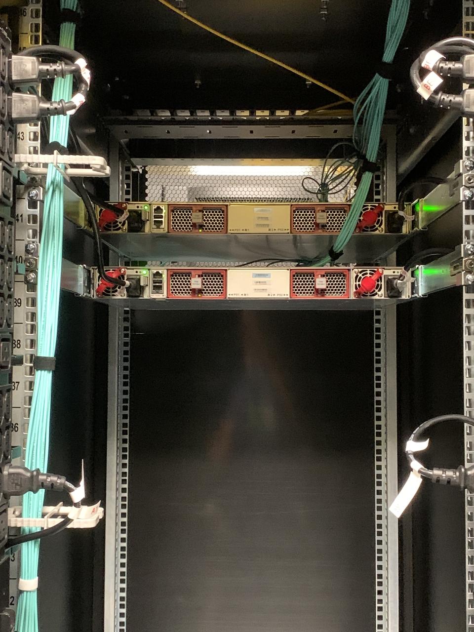 Top of an open rack with two PDUs and aqua fibre routed up the sides