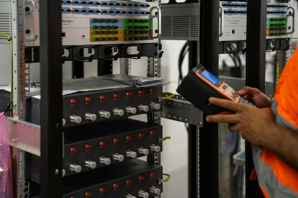 Technician checking rack equipment with a handheld diagnostic tester